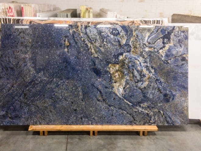 Blue Bahia granite slab with dark blue and gold veining on a wooden cradle.