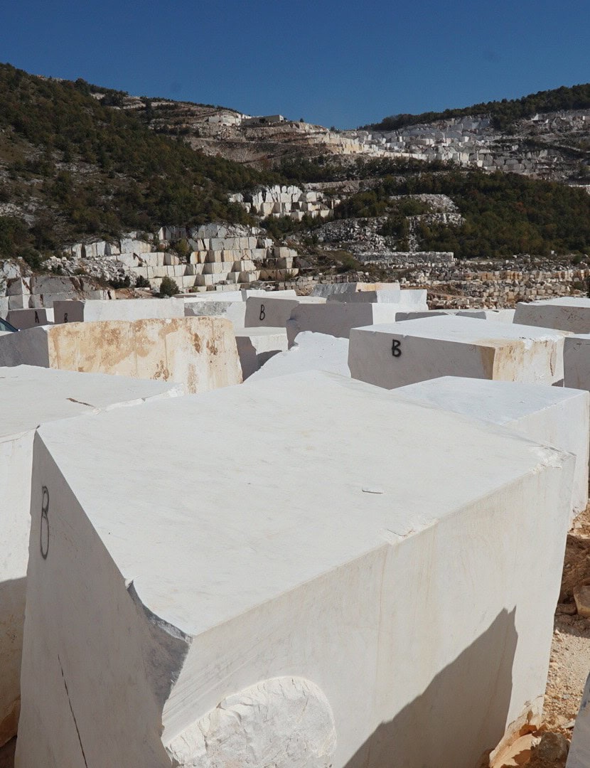 Large white marble blocks at the quarry with the hillside behind